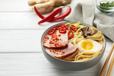 Photo of Delicious ramen in bowl on white wooden table, space for text. Noodle soup