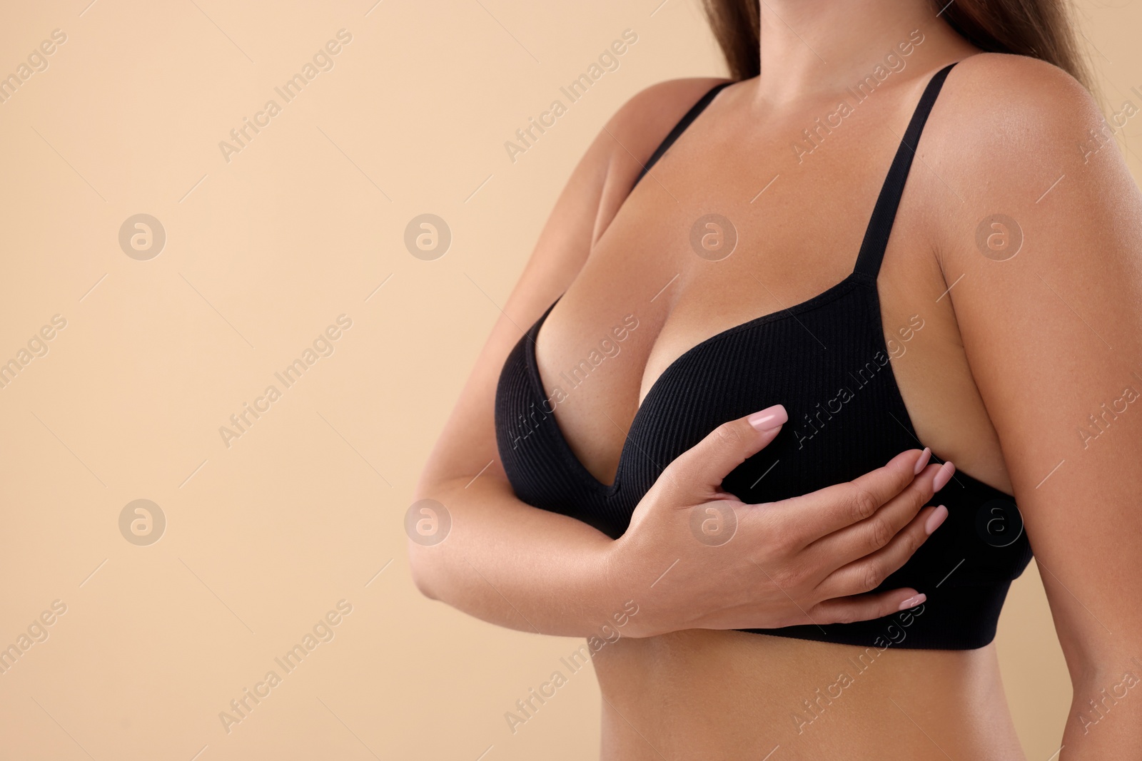 Photo of Woman with beautiful breast on beige background, closeup. Space for text