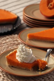 Piece of fresh homemade pumpkin pie with whipped cream on table