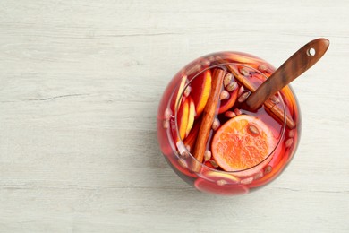 Photo of Glass bowl of aromatic punch drink on white wooden table, top view. Space for text