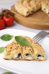 Photo of Piece of delicious puff pastry with spinach on table, closeup