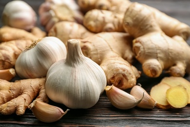 Photo of Ginger and garlic on black wooden table, closeup. Natural cold remedies