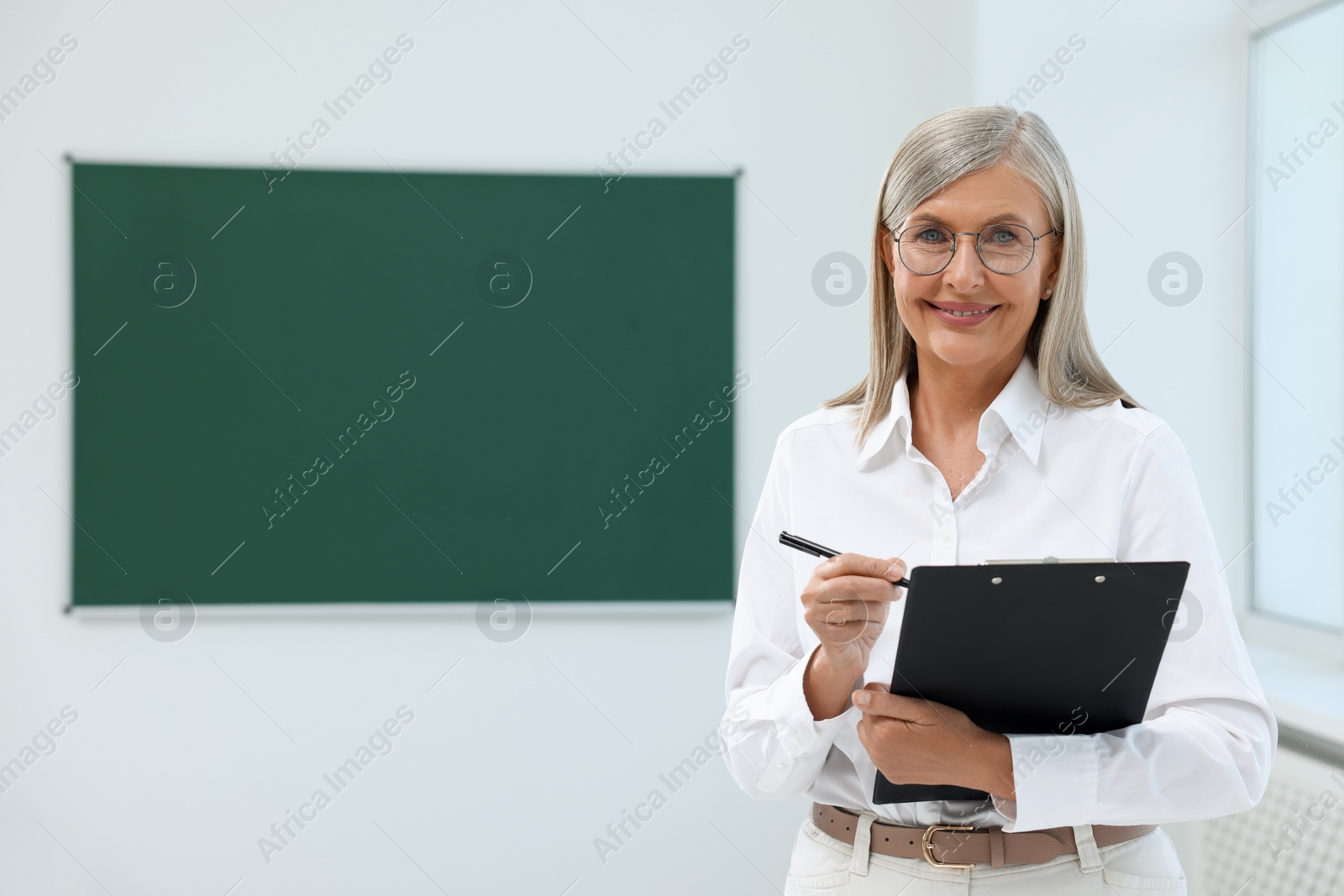 Photo of Portrait of happy professor with clipboard and pen in classroom, space for text