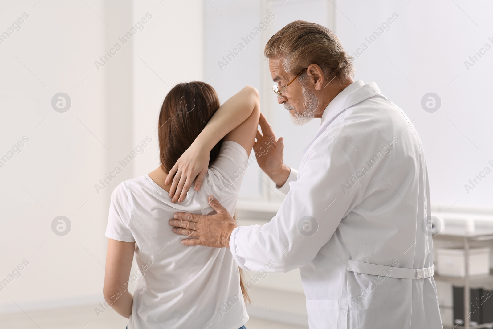 Photo of Professional orthopedist examining patient's shoulder in clinic