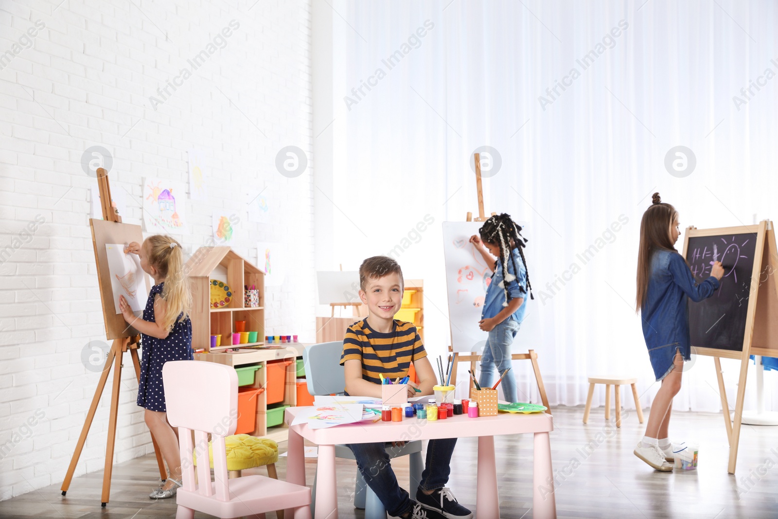 Photo of Cute little children drawing at painting lesson indoors