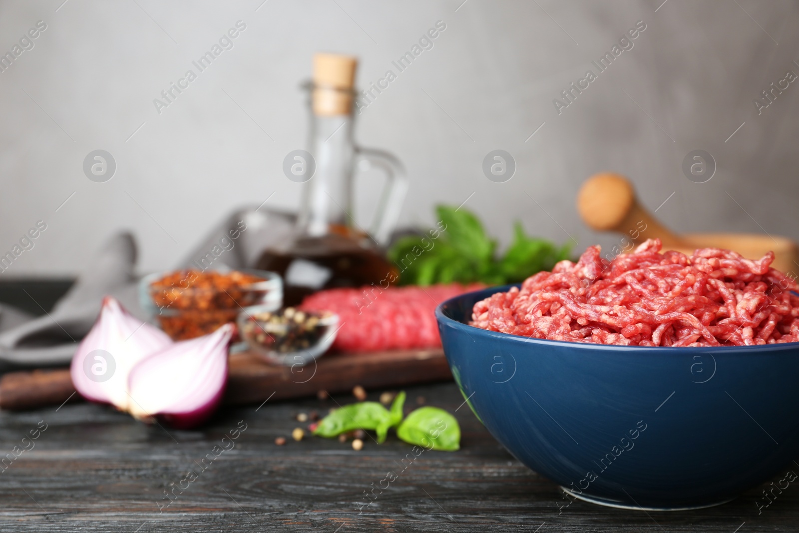 Photo of Fresh raw minced meat and vegetables on black wooden table