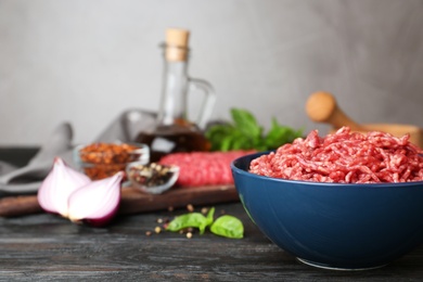 Photo of Fresh raw minced meat and vegetables on black wooden table