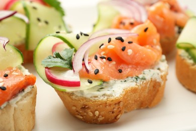 Photo of Tasty canapes with salmon served on table, closeup