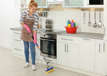 Woman cleaning floor with mop in kitchen