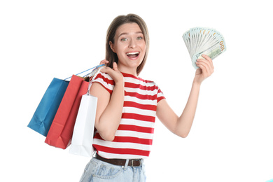 Emotional young woman with money and shopping bags on white background