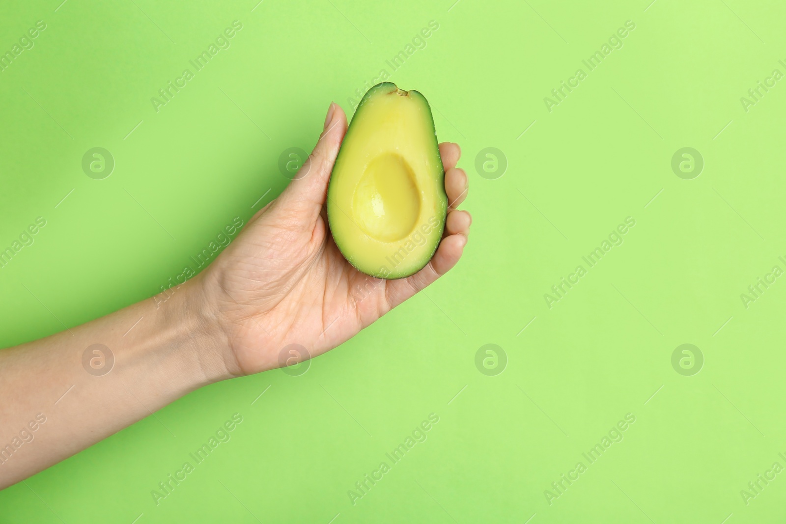 Photo of Woman holding ripe cut avocado on color background