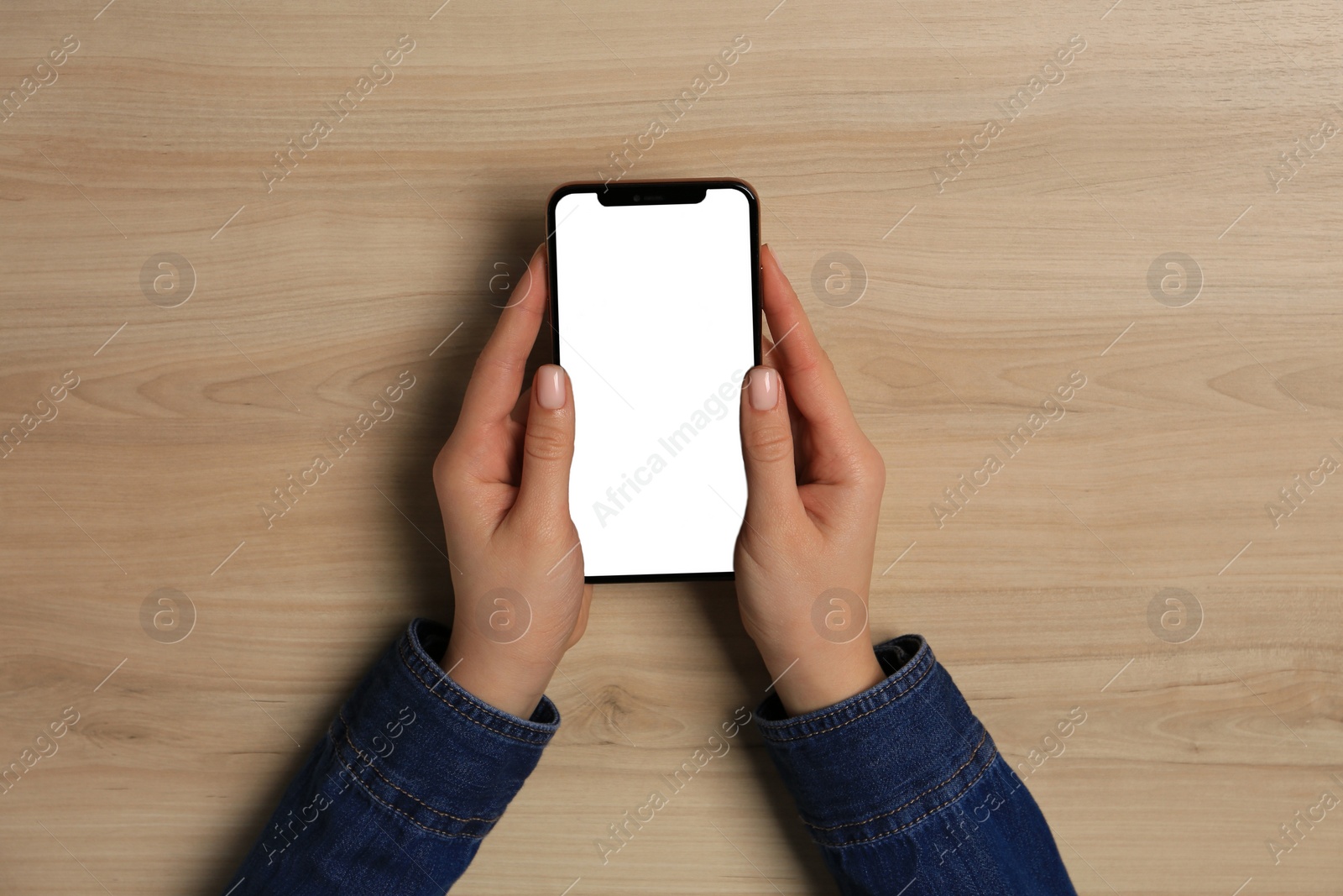 Photo of Woman with smartphone at wooden table, top view