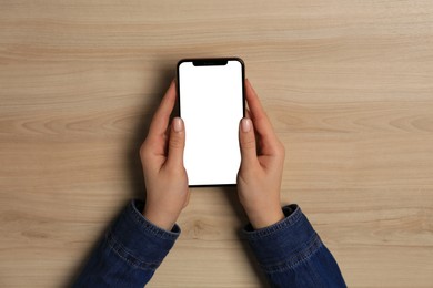 Photo of Woman with smartphone at wooden table, top view