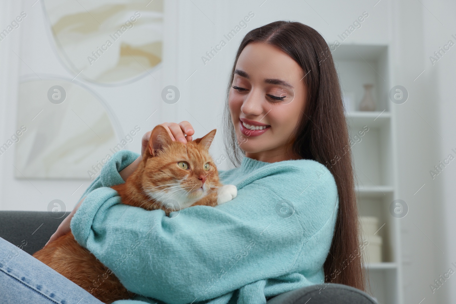 Photo of Beautiful woman petting cute cat at home