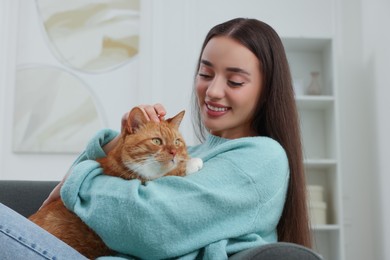 Photo of Beautiful woman petting cute cat at home