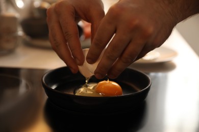 Photo of Man cooking egg in small frying pan, closeup