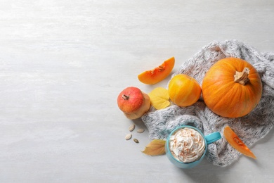 Flat lay composition with cup of pumpkin spice latte, autumn decor and space for text on light table