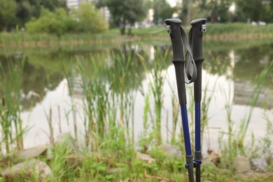 Photo of Two Nordic walking poles near lake outdoors. Space for text