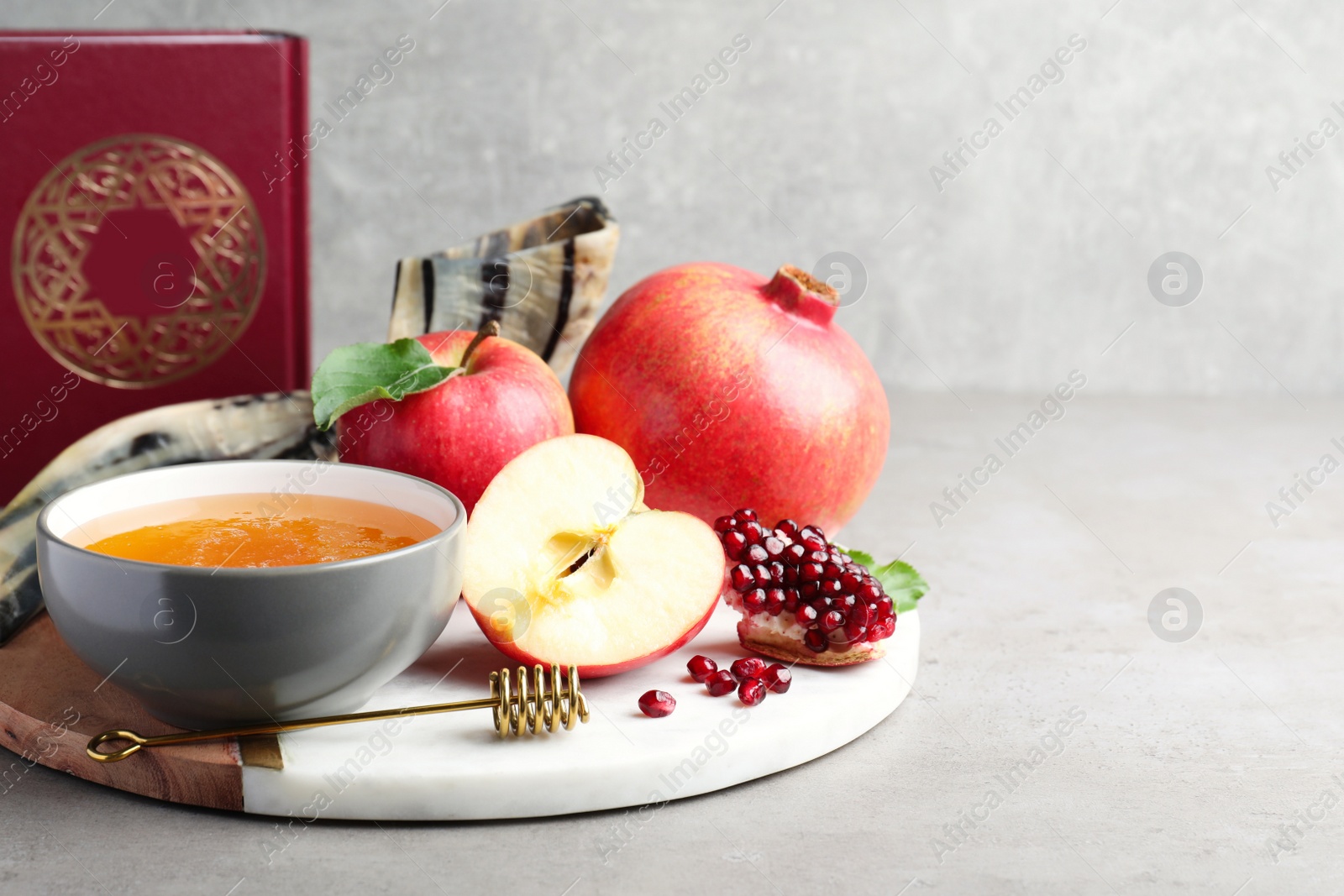 Photo of Honey, pomegranate, apples, shofar and Torah on grey table. Rosh Hashana holiday