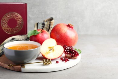 Photo of Honey, pomegranate, apples, shofar and Torah on grey table. Rosh Hashana holiday
