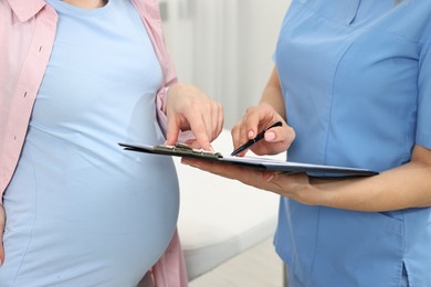 Photo of Doctor with results of laboratory test consulting pregnant patient in clinic, closeup