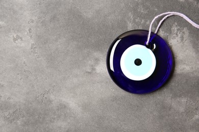 Photo of Evil eye amulet on grey table, top view. Space for text