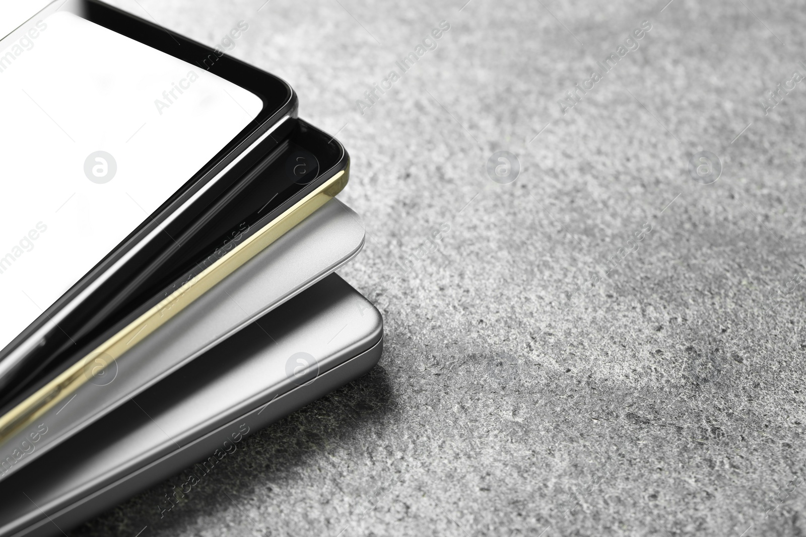 Photo of Stack of electronic devices on grey table, closeup. Space for text