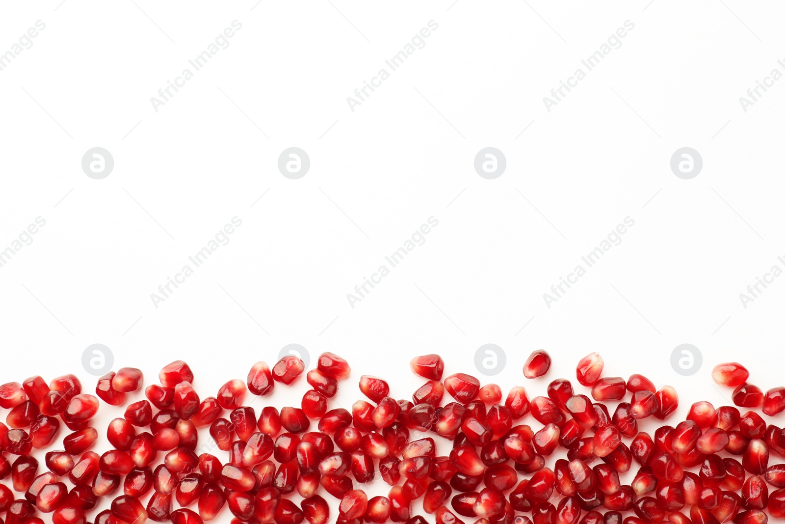 Photo of Many ripe juicy pomegranate grains on white background, flat lay. Space for text