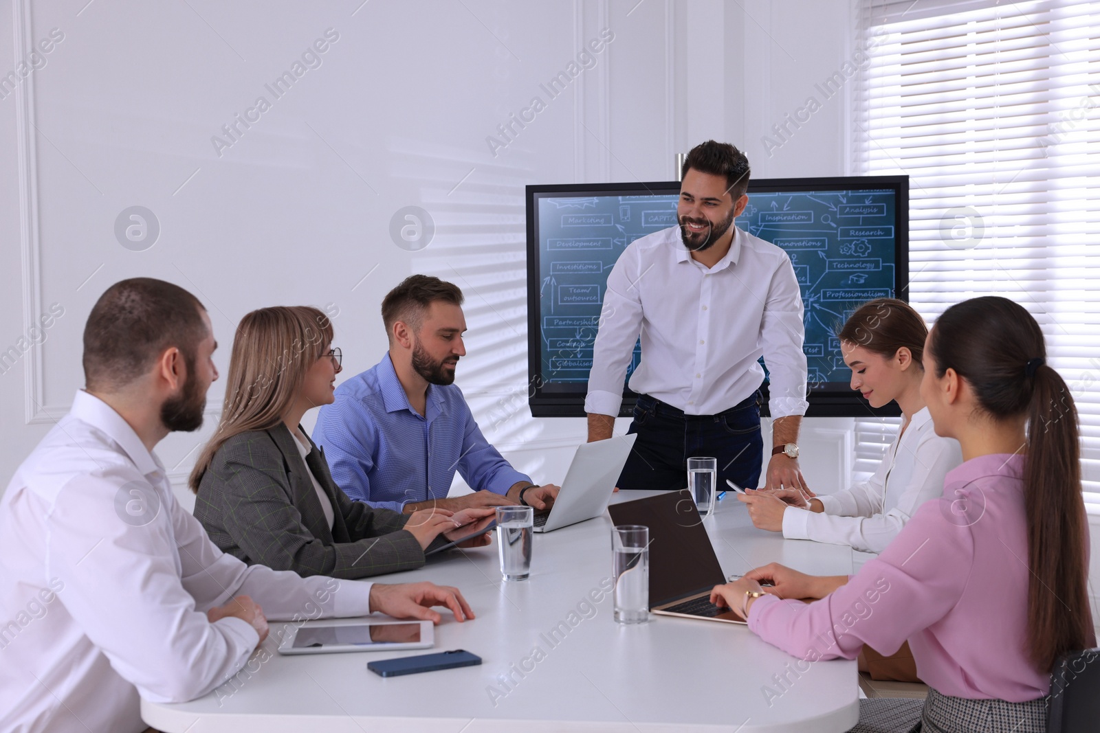 Photo of Business trainer near interactive board in meeting room during presentation