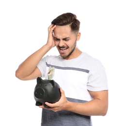 Photo of Portrait of emotional young man holding piggy bank with money on white background