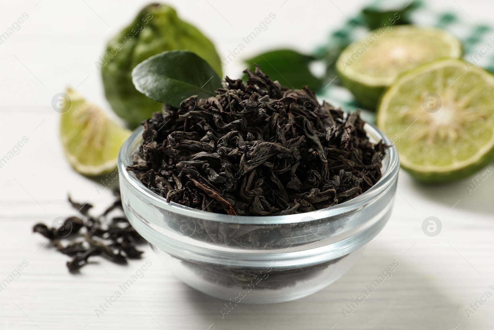 Photo of Dry bergamot tea leaves and fresh fruits on white wooden table, closeup