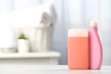 Bottles with hair care cosmetics on table in bathroom, space for text