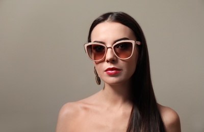 Photo of Beautiful woman in stylish sunglasses on beige background