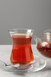 Photo of Glass of traditional Turkish tea and pot on light grey table