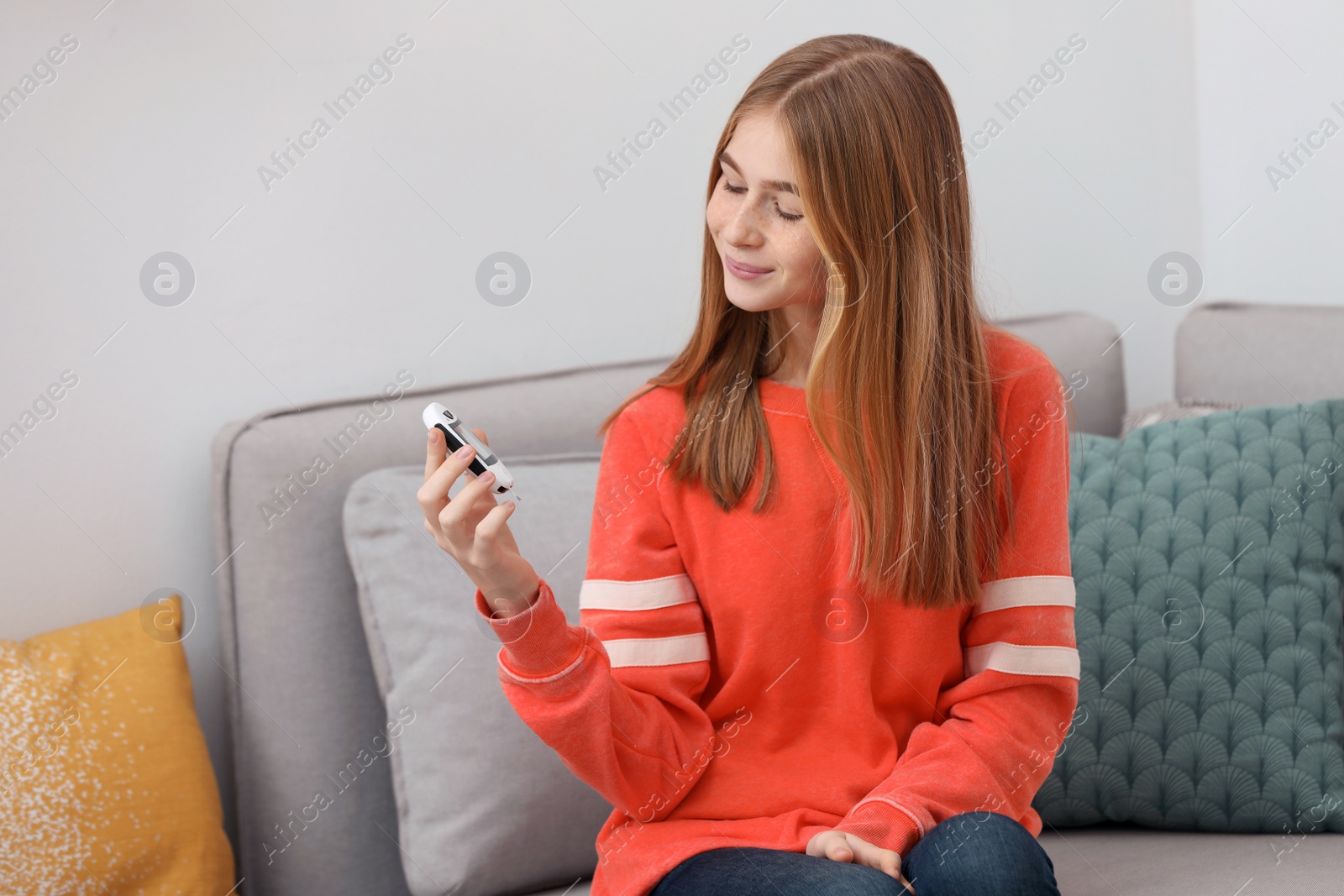 Photo of Teen girl holding digital glucometer at home. Diabetes control