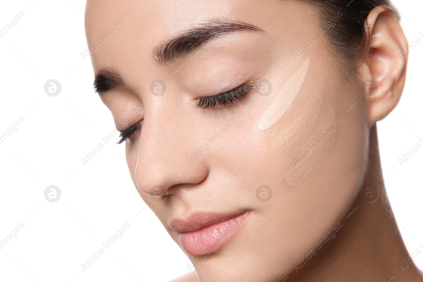 Photo of Young woman with different shades of skin foundation on her face against white background