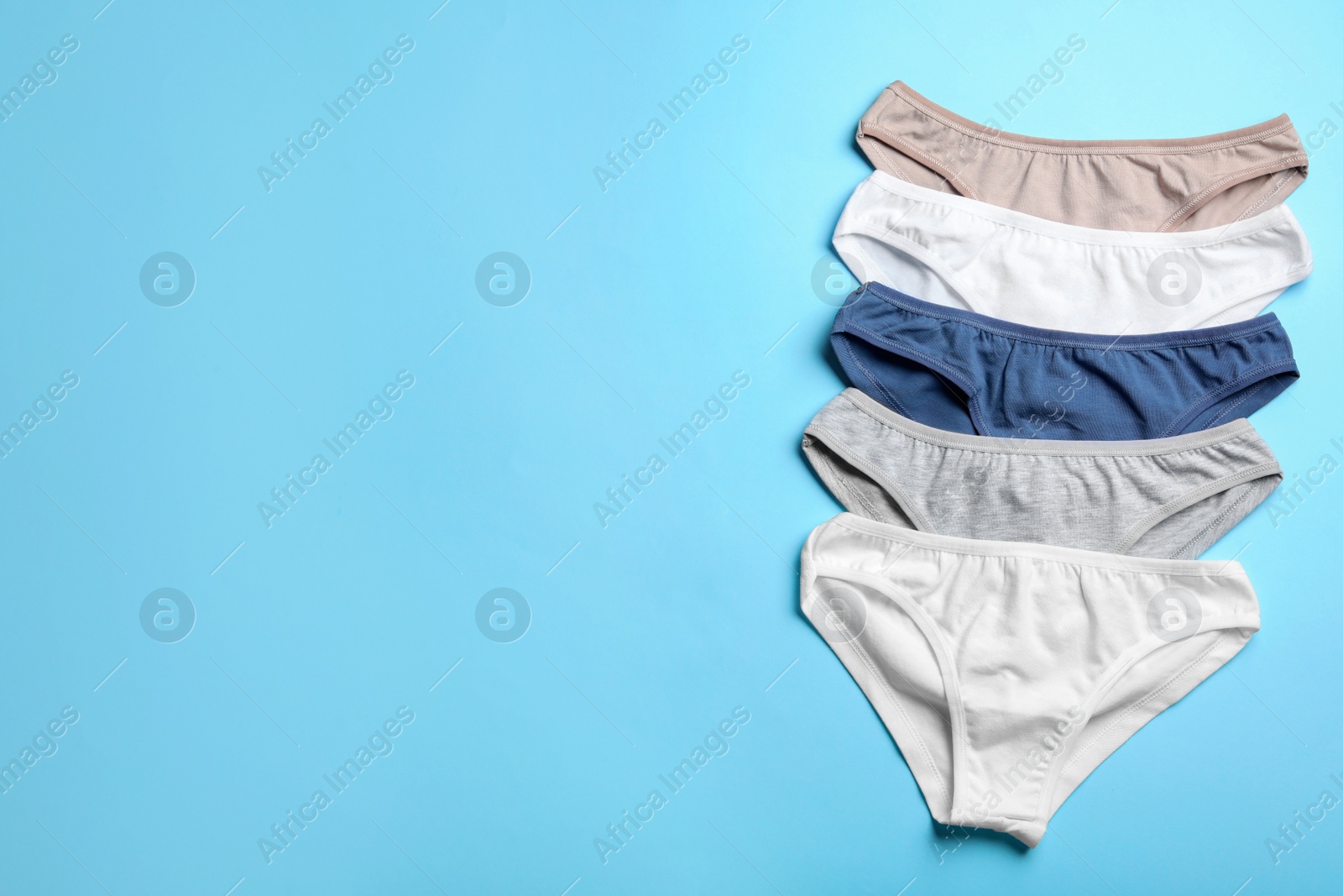 Photo of Women's underwear on light blue background, flat lay. Space for text