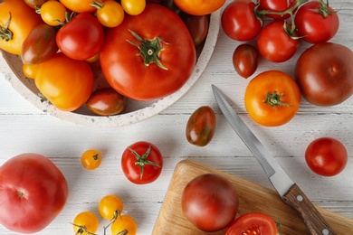 Photo of Flat lay composition with fresh ripe whole and cut tomatoes on white wooden table