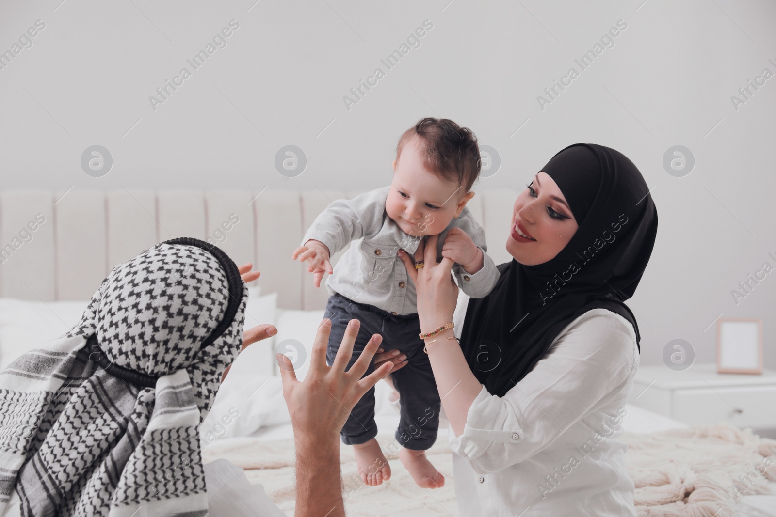 Photo of Happy Muslim family with little son in bedroom