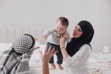 Happy Muslim family with little son in bedroom