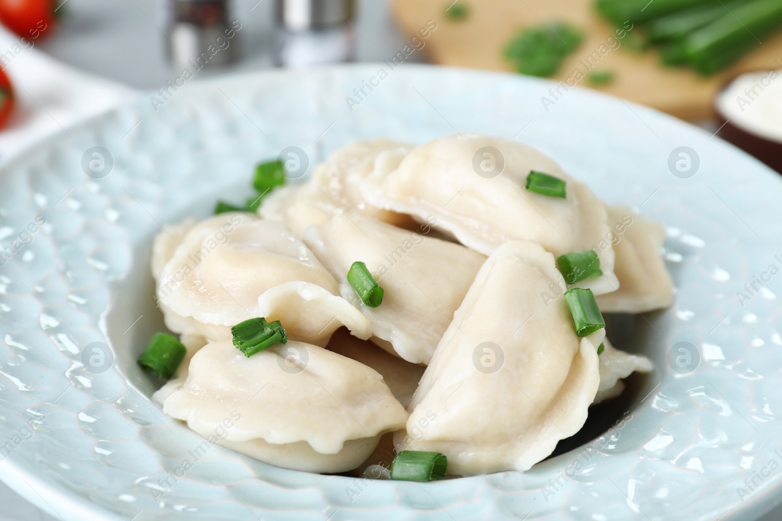 Photo of Tasty dumplings served with green onion on plate, closeup