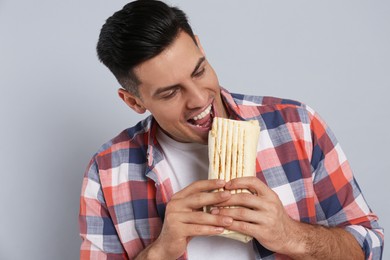 Man eating delicious shawarma on grey background