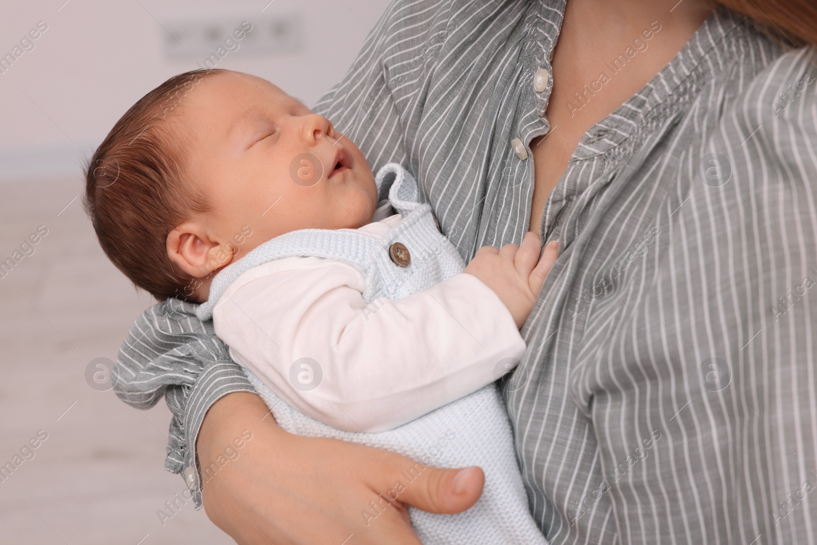 Photo of Mother holding her cute newborn baby indoors, closeup