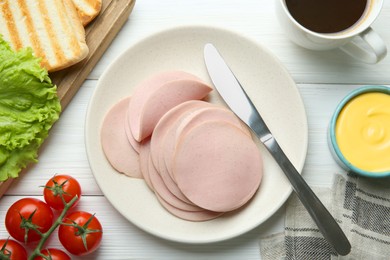 Photo of Slices of delicious boiled sausage served on white wooden table, flat lay