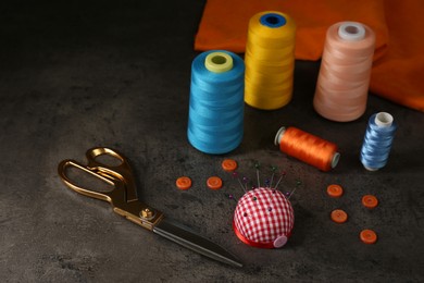 Photo of Composition with different sewing items and fabric on grey stone table