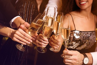 Photo of Friends with glasses of sparkling wine celebrating New Year, closeup