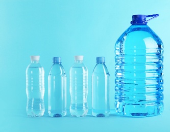 Photo of Large and small bottles with pure water on color background