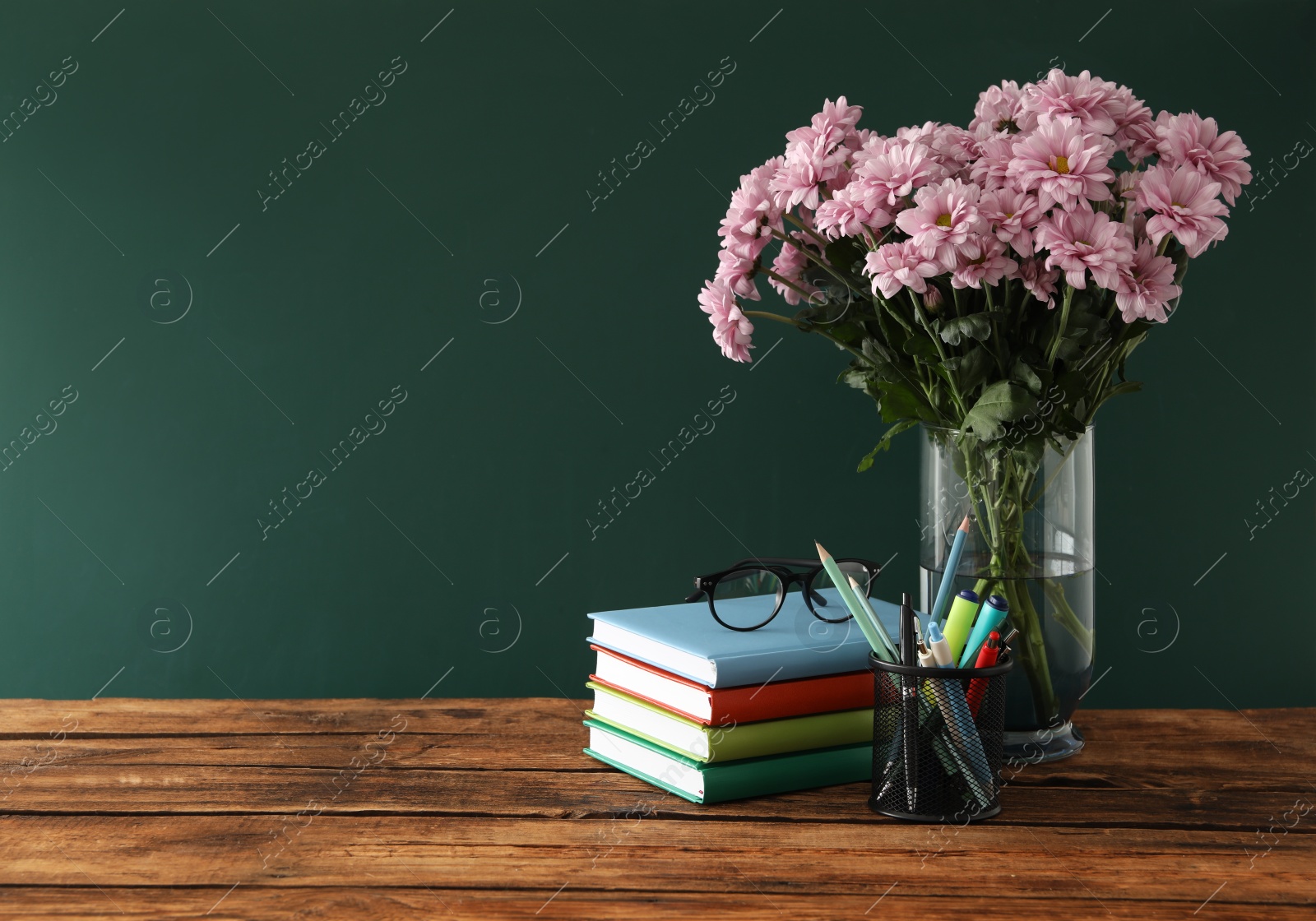 Photo of Set of stationery and flowers on wooden table near chalkboard, space for text. Teacher's Day