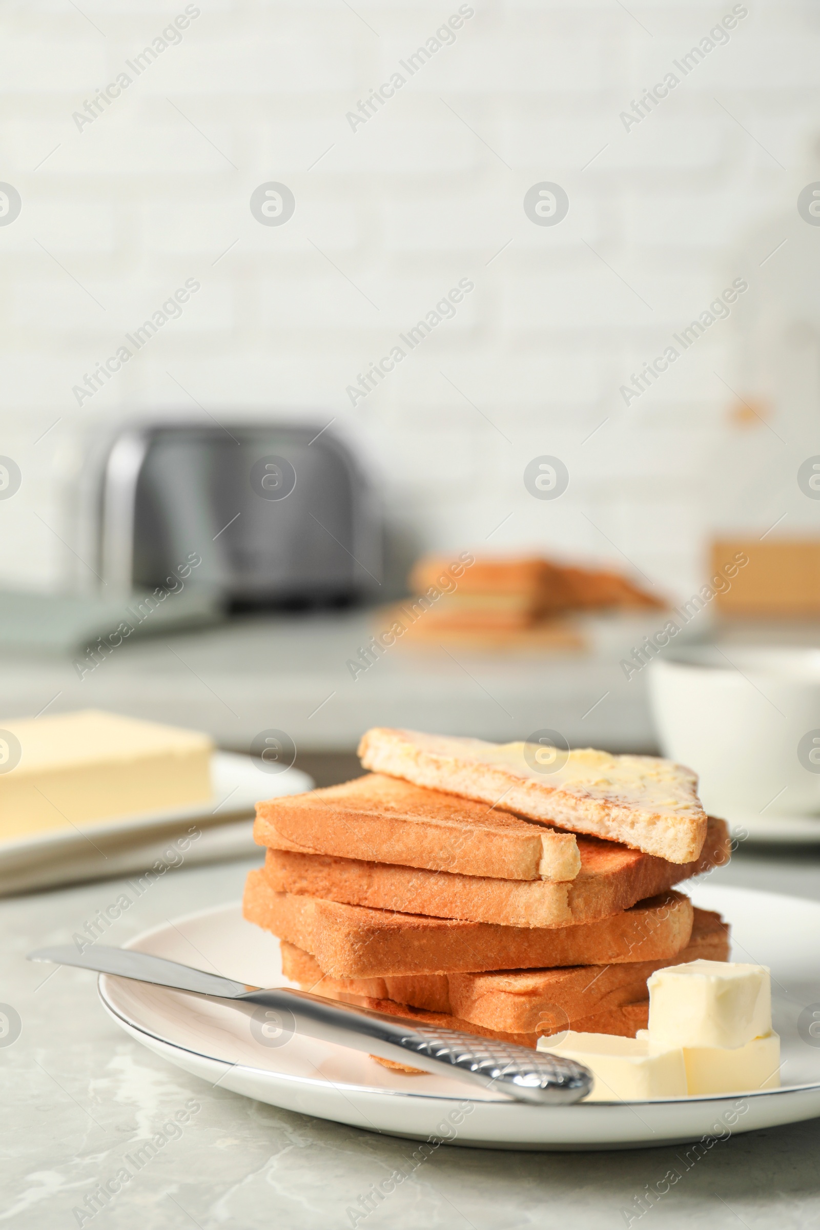 Photo of Tasty toasts with butter served on grey marble table