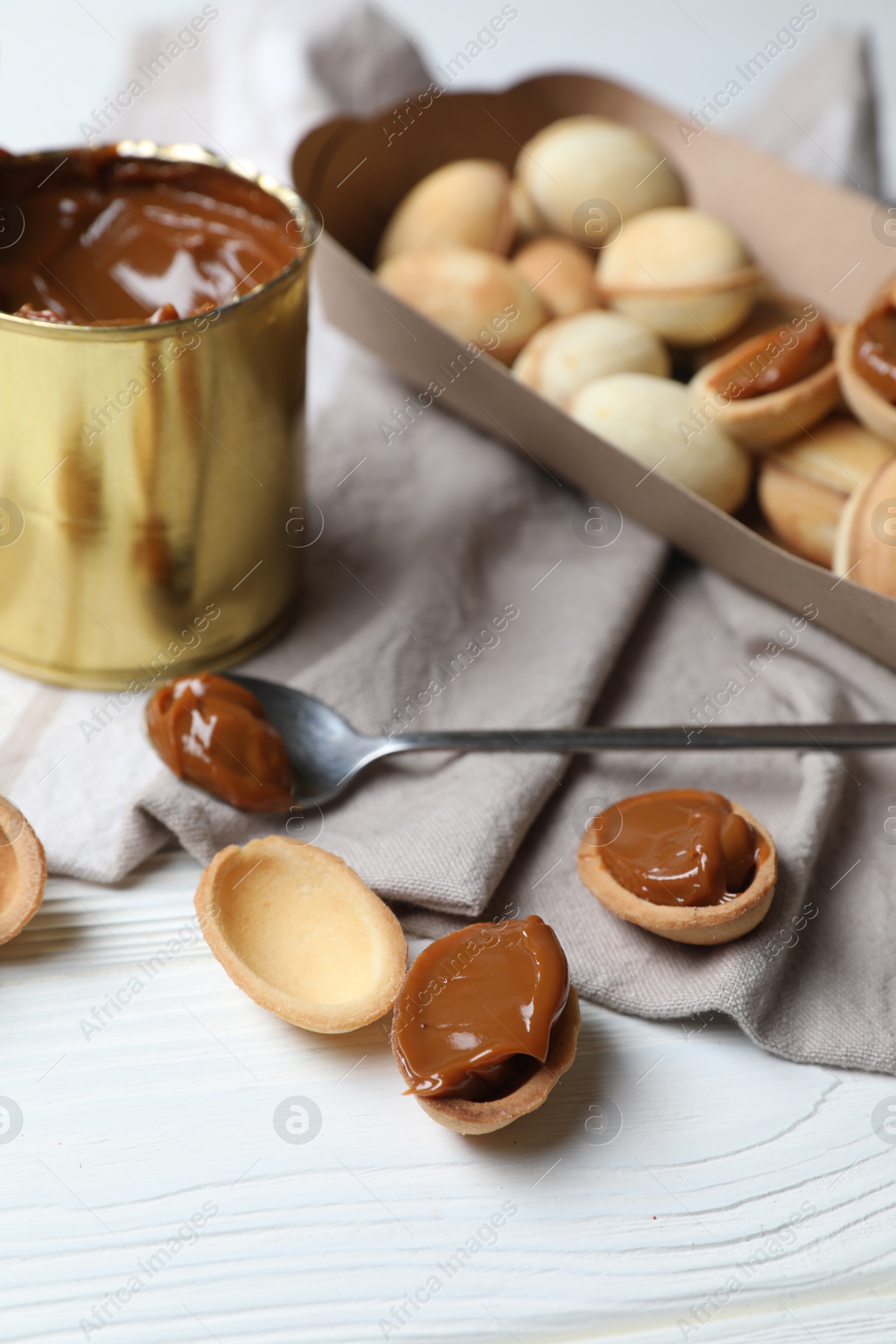 Photo of Delicious walnut shaped cookies with condensed milk on white wooden table, closeup